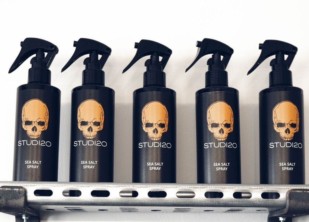 Studio120 sea salt spray bottles, sleek black with skull logo, on display rack in Bushey, England, GB.