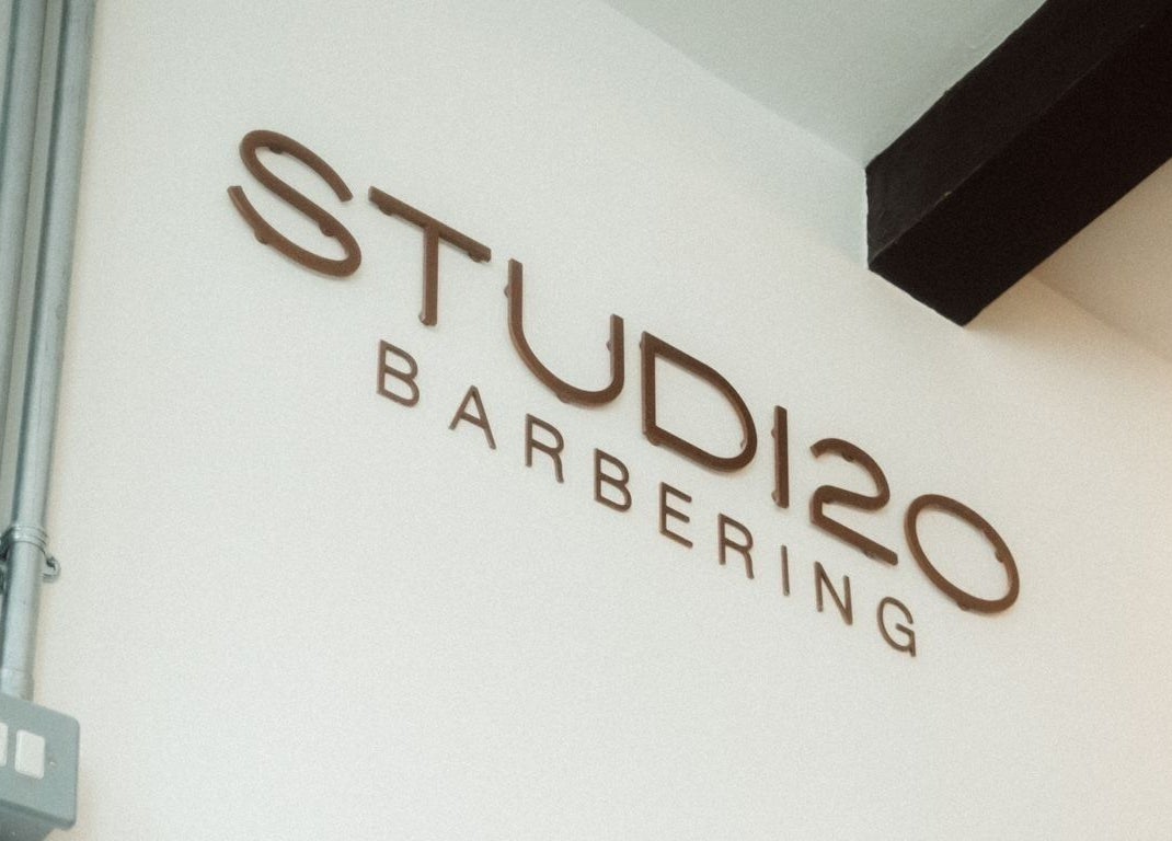Studio120 barbering sign on a white wall in Bushey, England, GB.