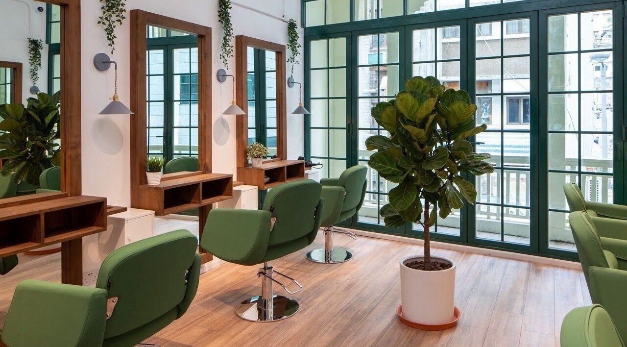 Stylish interior of Love Hair HK salon on Hong Kong Island with green chairs and natural decor.