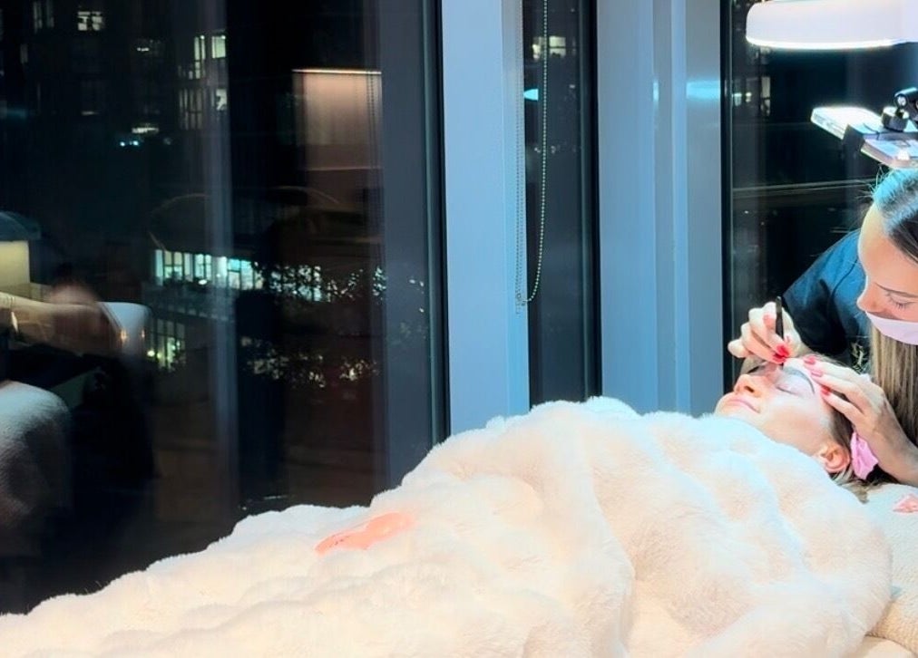 Aesthetician at La Maison de Beauté - St Leonards performing a facial under soft evening light. St Leonards, New South Wales, AU.