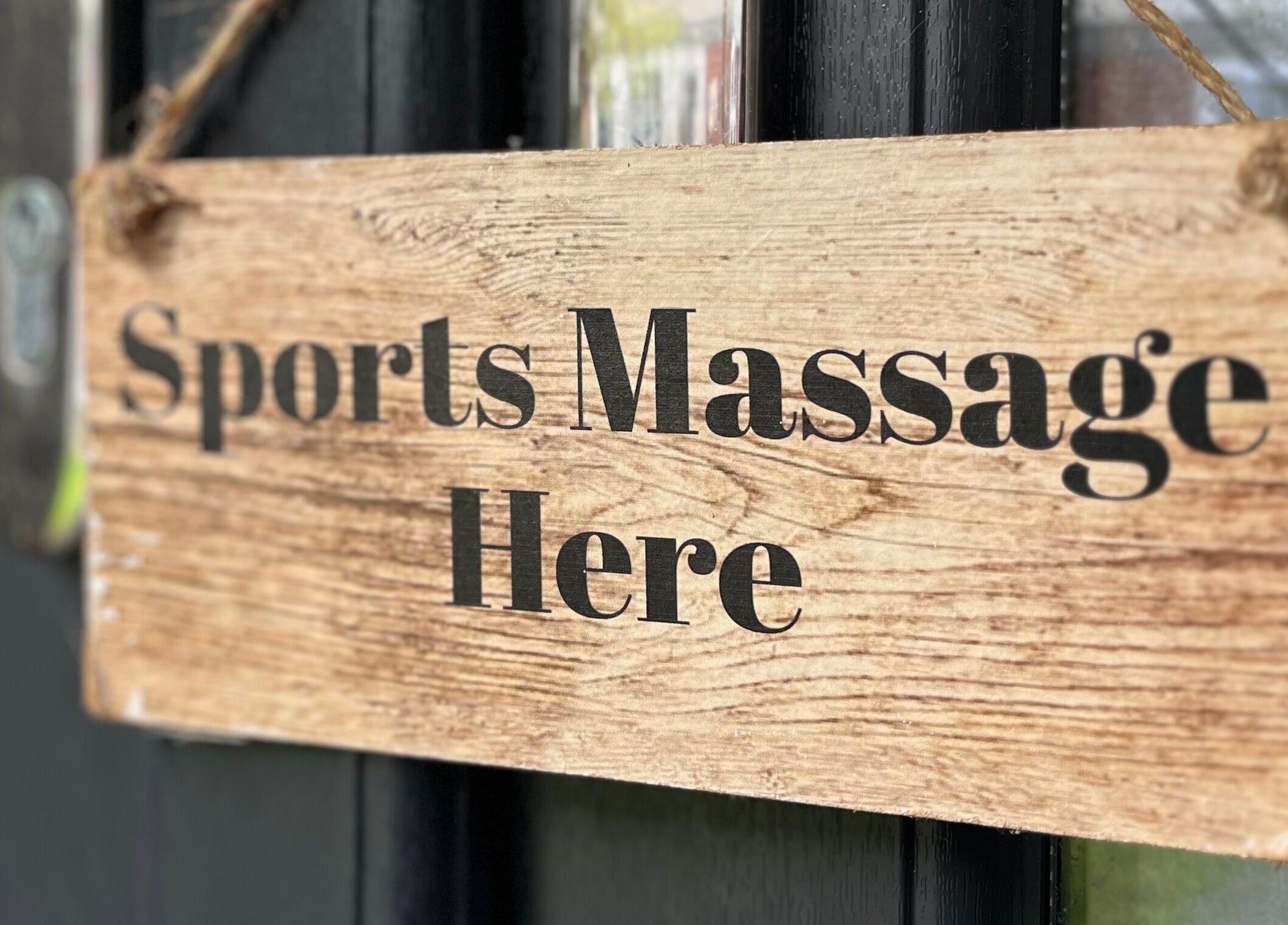 Wooden sign reading 'Sports Massage Here' at Sports Massage with Paula, Llandudno Junction, Wales, GB.