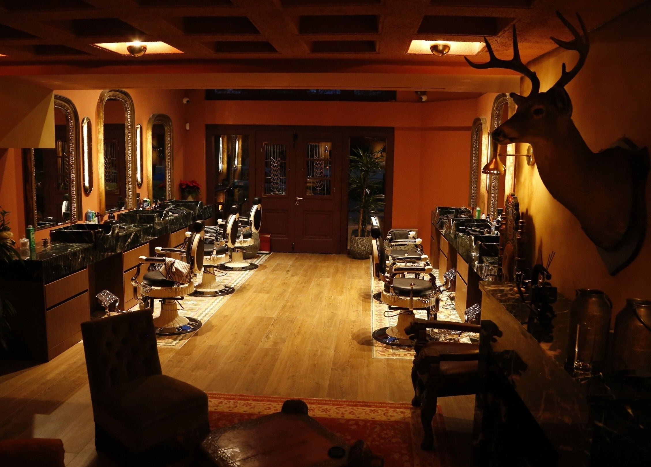 Warm, inviting interior of Hemingway Gentlemen’s Guild, Iraklio Athens, GR, featuring classic barber chairs.