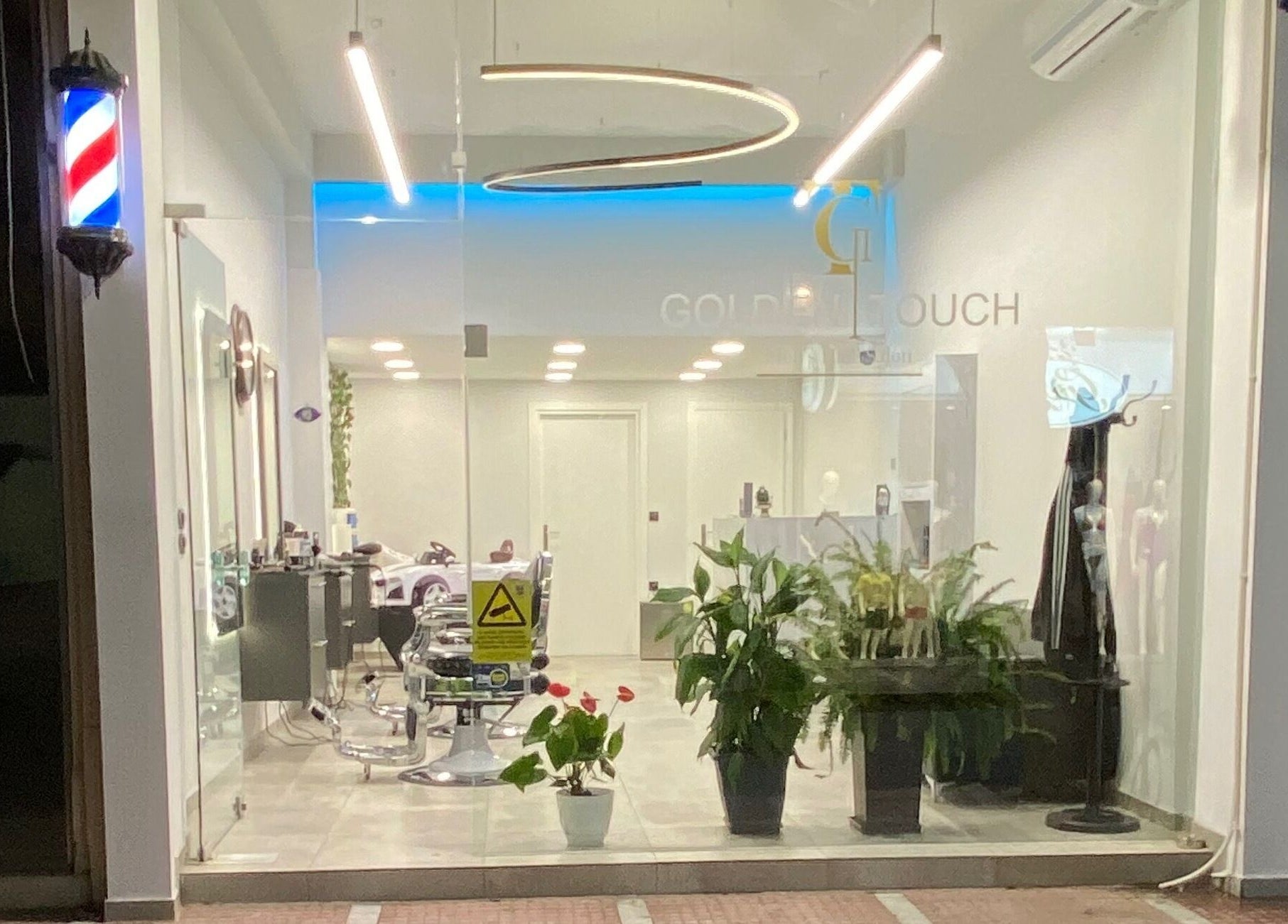 Εξωτερική όψη του Golden Touch MensHair στο Μέγαρα, GR με κομψή διακόσμηση και φυτά.