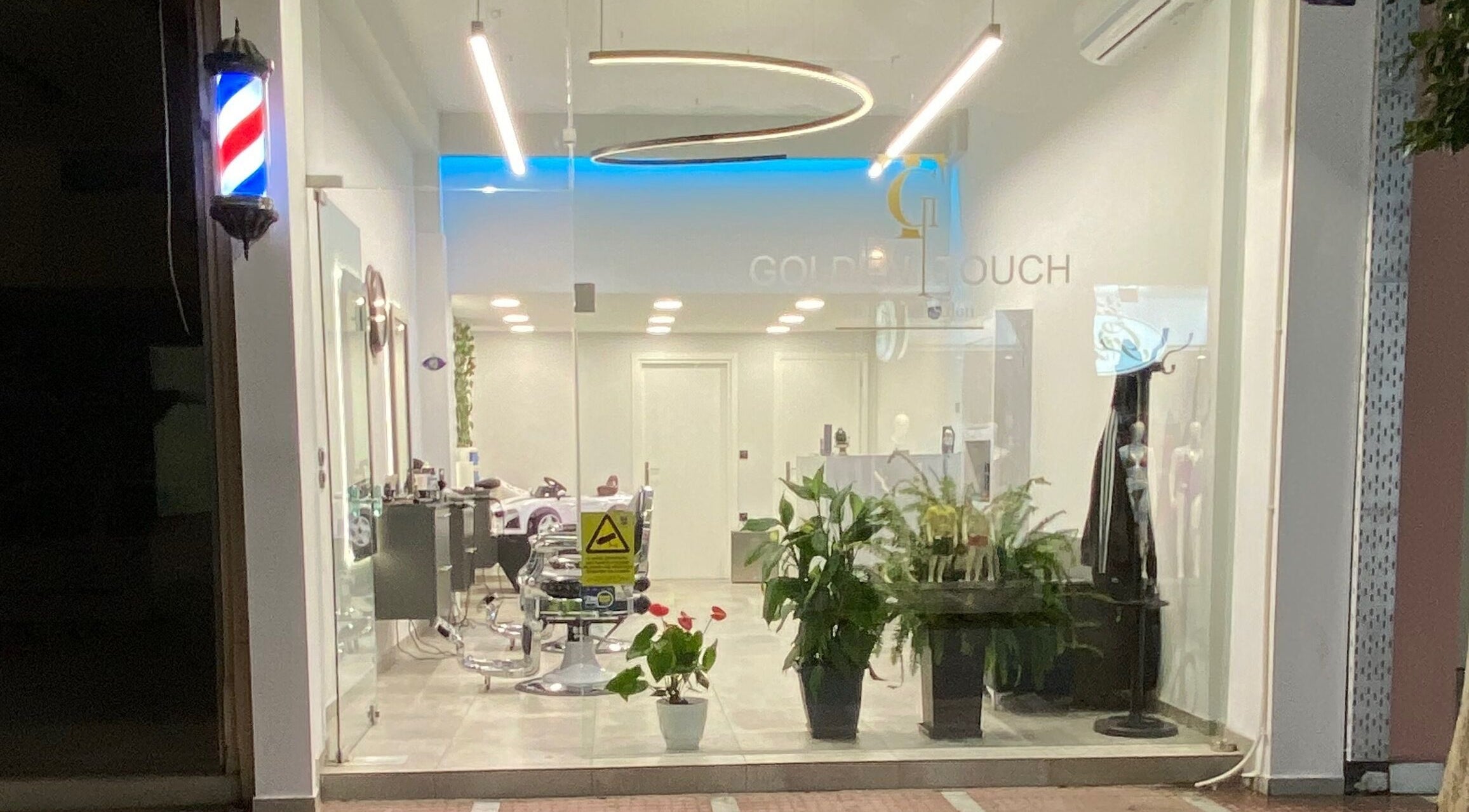 Εξωτερική όψη του Golden Touch MensHair στο Μέγαρα, GR με κομψή διακόσμηση και φυτά.