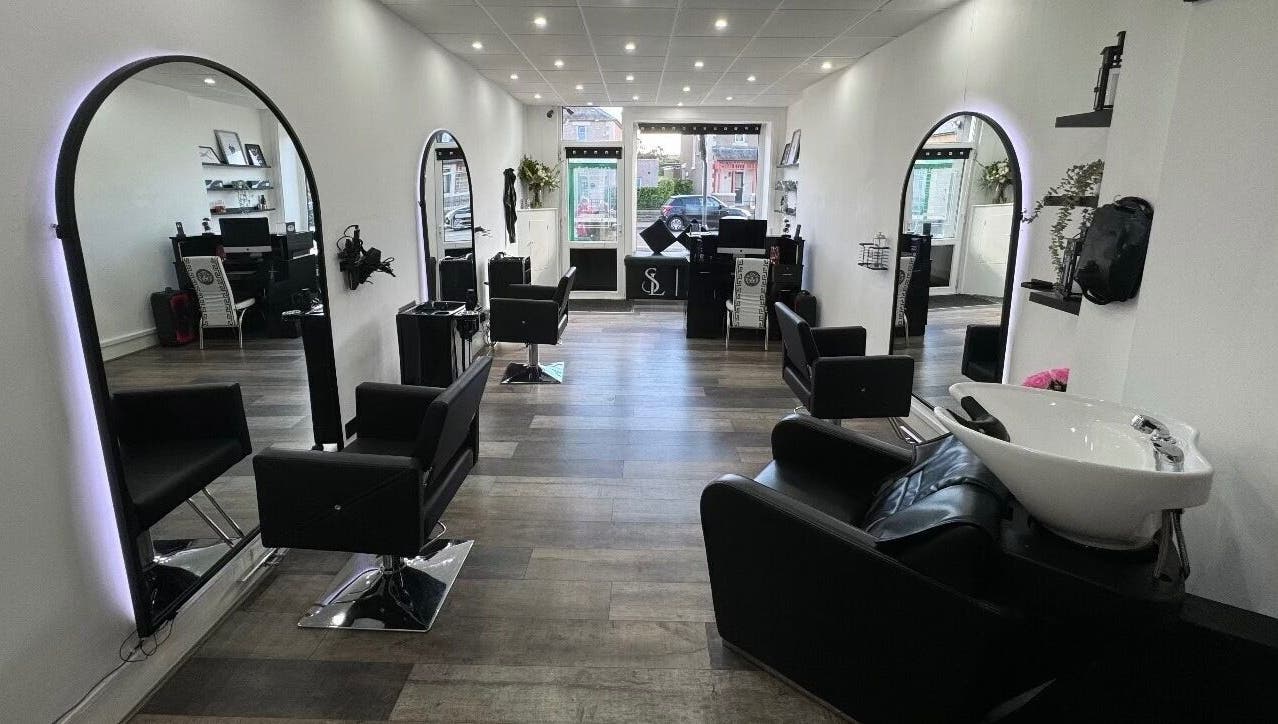Modern interior of S & L Hair Studio in Newtongrange, Scotland featuring sleek black chairs and mirrors.