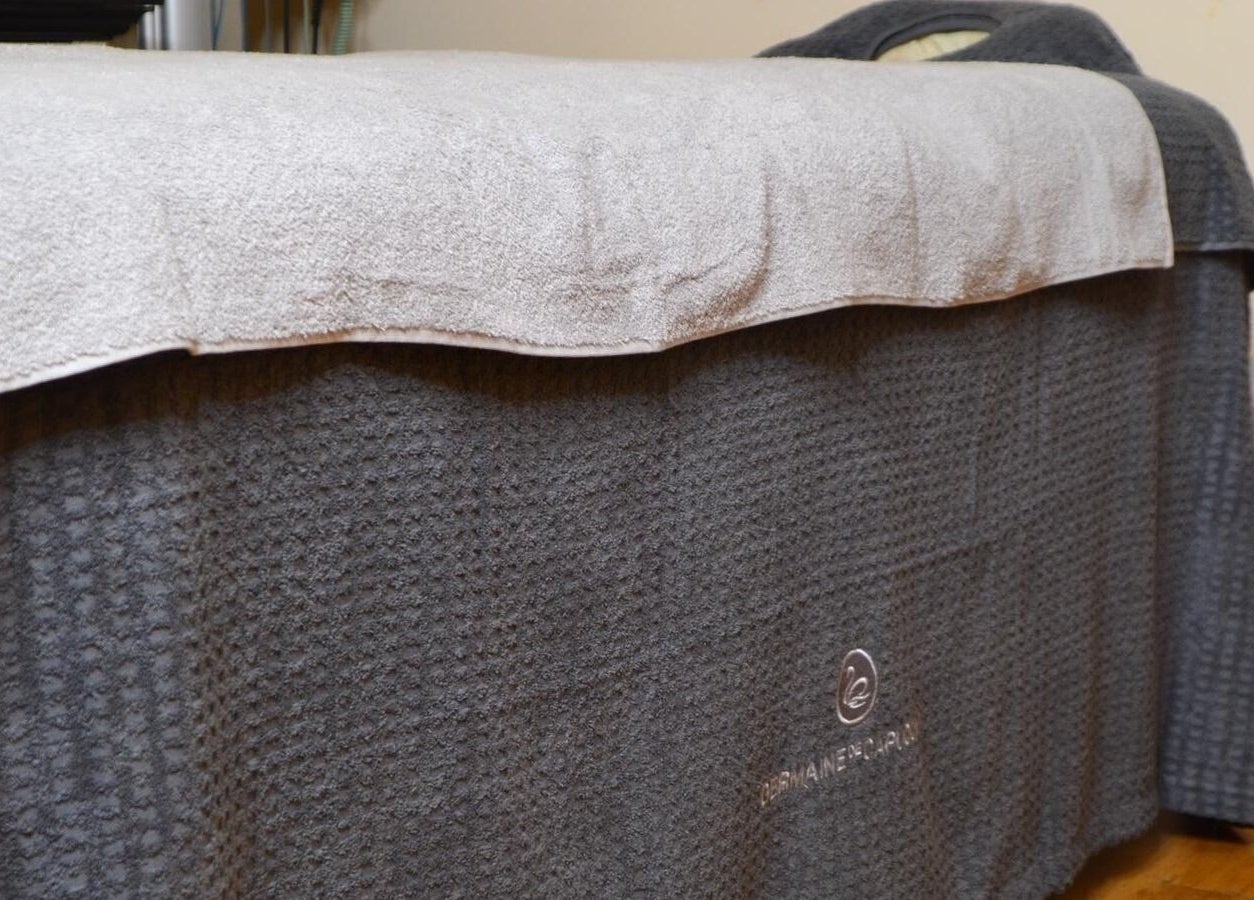 Comfortable spa bed at La Belle Vita Wellness, Rye, England, GB, with plush grey towels.