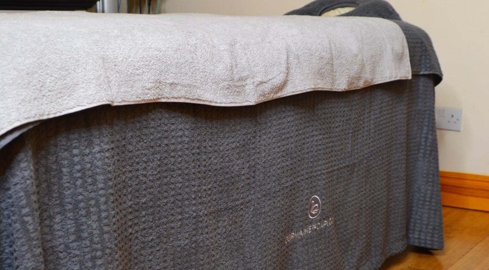 Comfortable spa bed at La Belle Vita Wellness, Rye, England, GB, with plush grey towels.