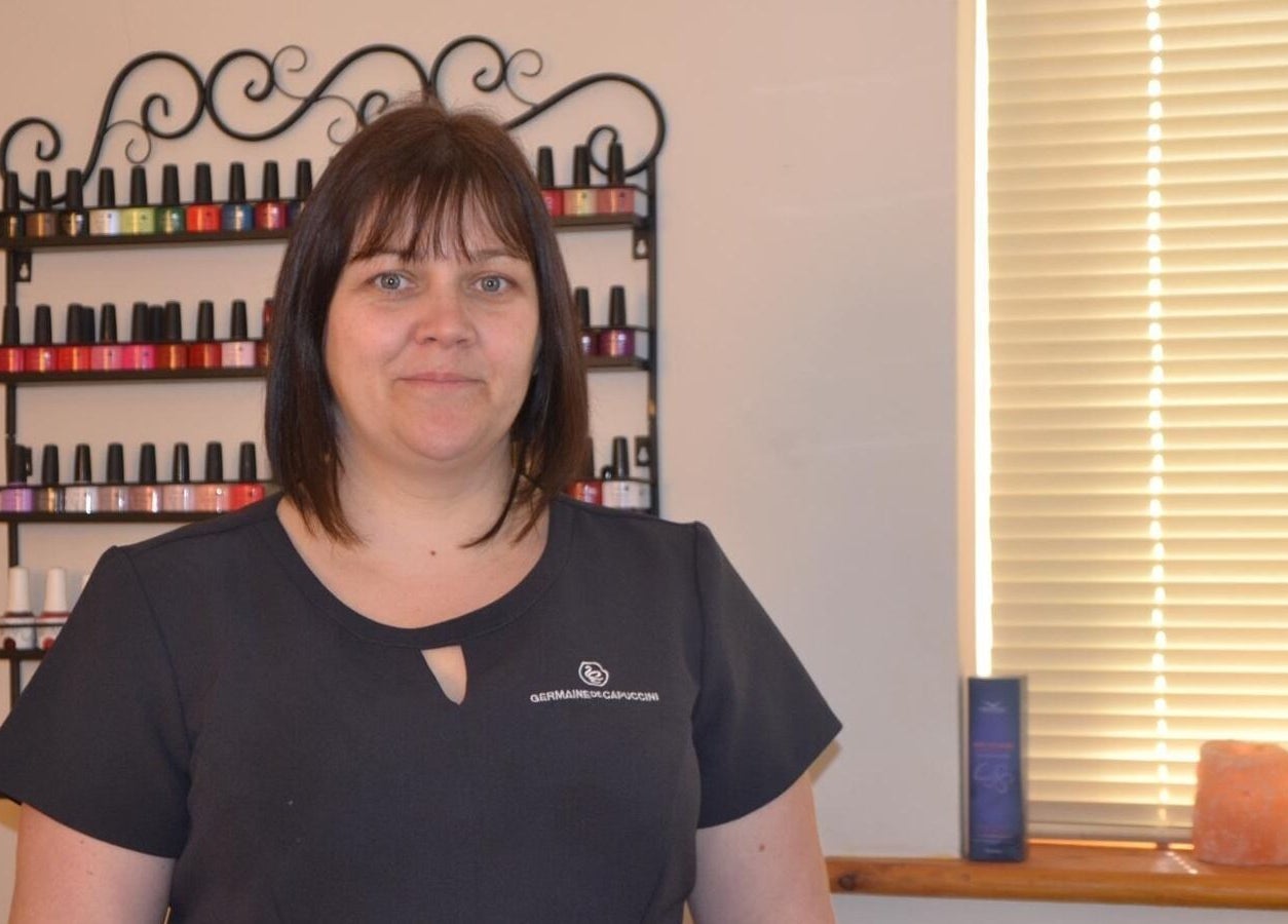 Staff member at La Belle Vita Wellness, Rye, England, standing by colorful nail polish display.