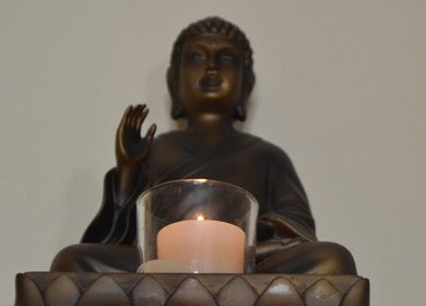 Bronze Buddha statue with candle at La Belle Vita Wellness, Rye, England, GB.