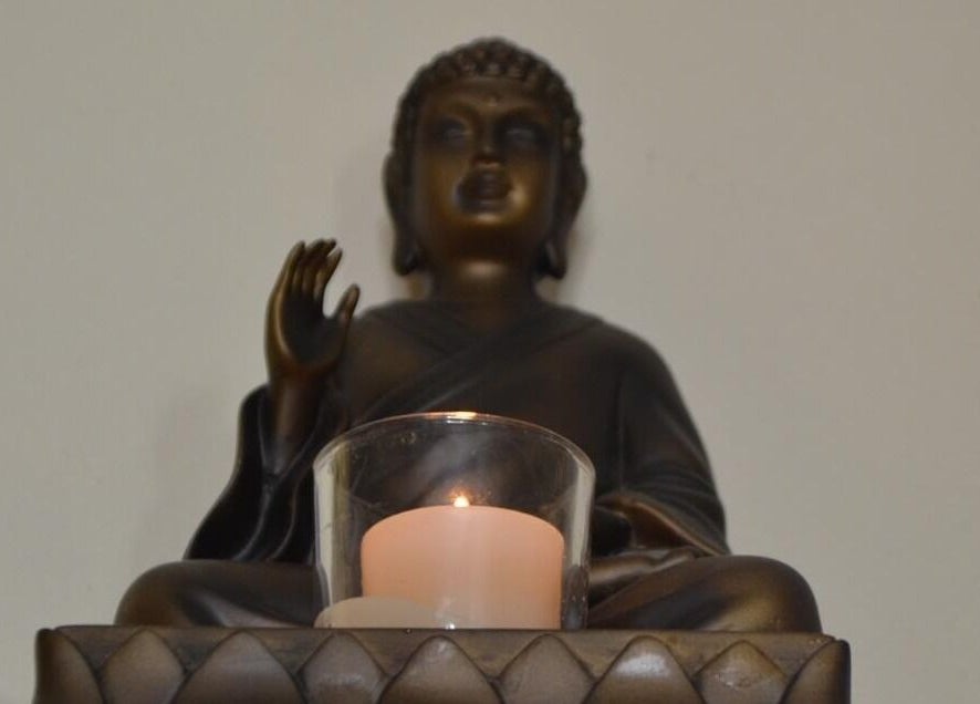 Bronze Buddha statue with candle at La Belle Vita Wellness, Rye, England, GB.