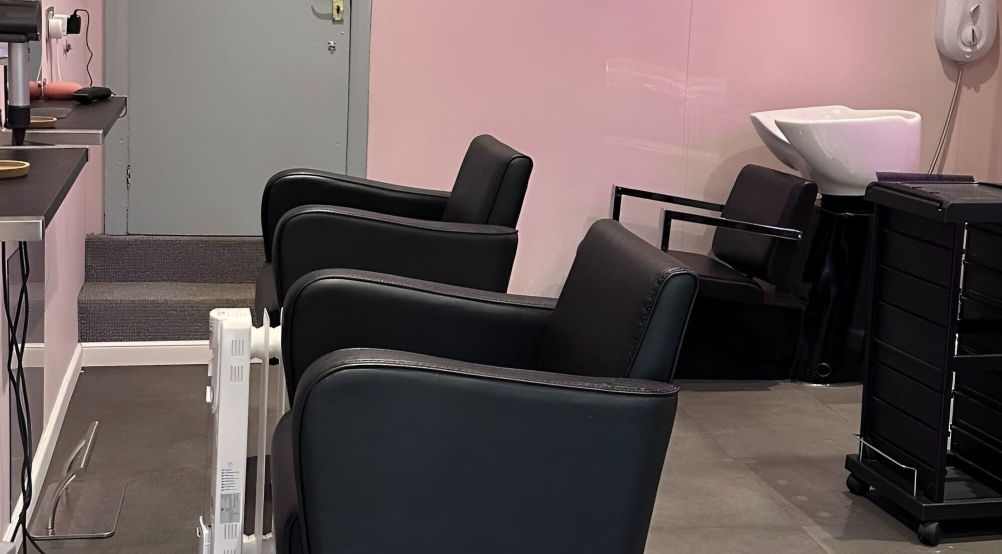Interior of Hair Made Fabulous salon in Pleasley, England, showcasing elegant black chairs and modern washing station.