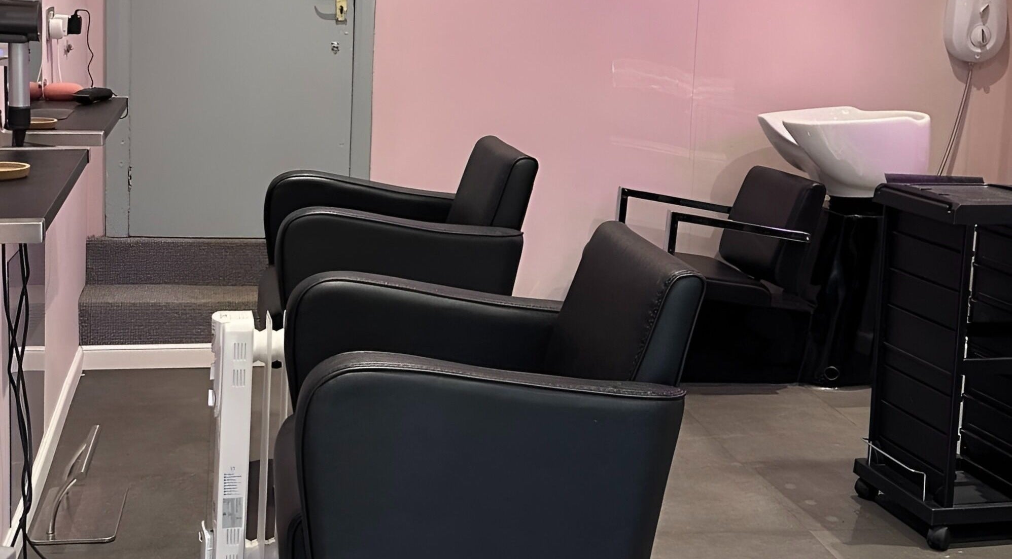 Interior of Hair Made Fabulous salon in Pleasley, England, showcasing elegant black chairs and modern washing station.