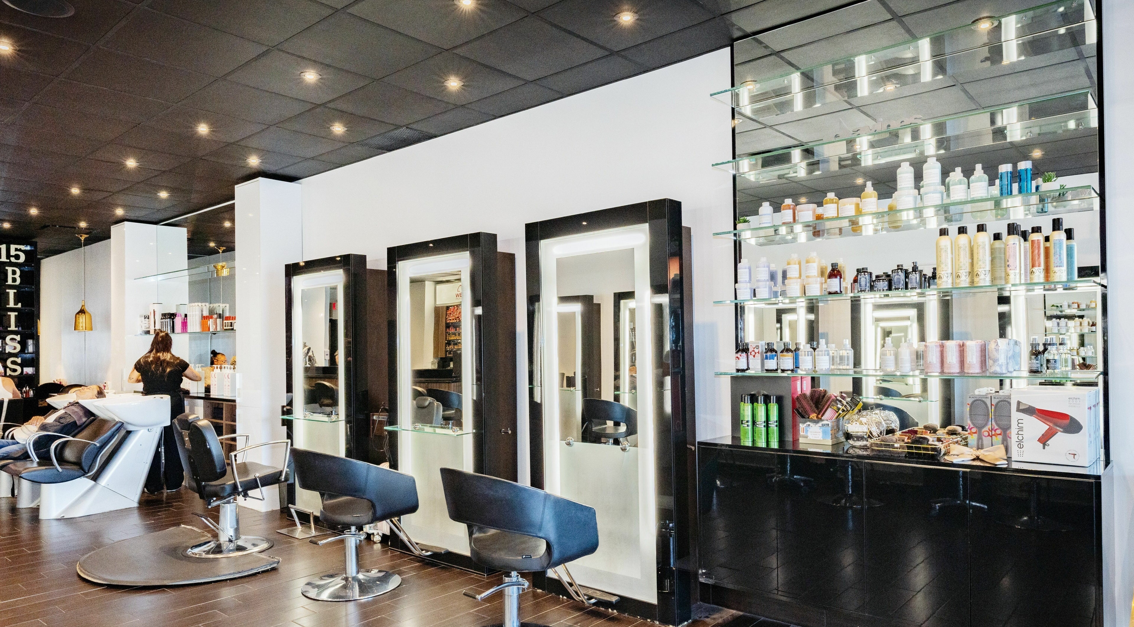 Interior of Salon Bliss MTL, showcasing modern hair stations and product displays in Dollard-des-Ormeaux, Québec, CA.