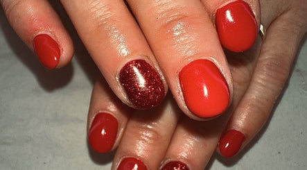 Close-up of vibrant red nails with a glitter accent at Sun Kissed Nail & Wax Studio, Thurso, Scotland, GB.
