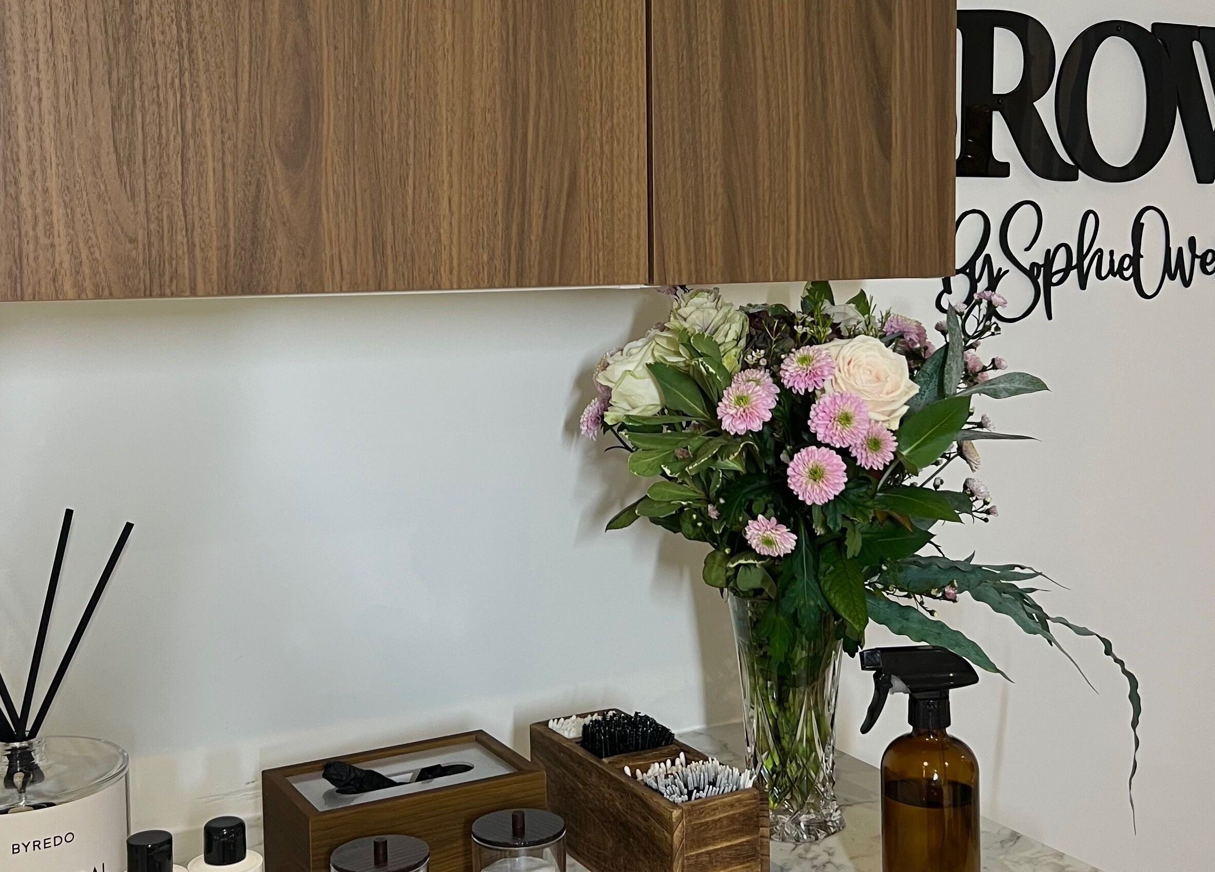 Chic interior at Sophz Browz, Barry, Wales, GB, with elegant flowers and beauty products on display.