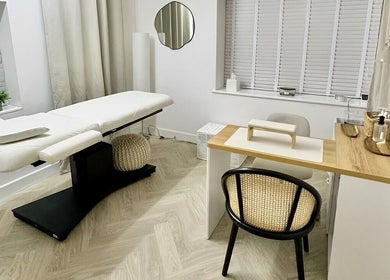 Cozy treatment room at The Lookery Beauty Room, Milton Keynes, England, GB, featuring a massage bed and nail station.