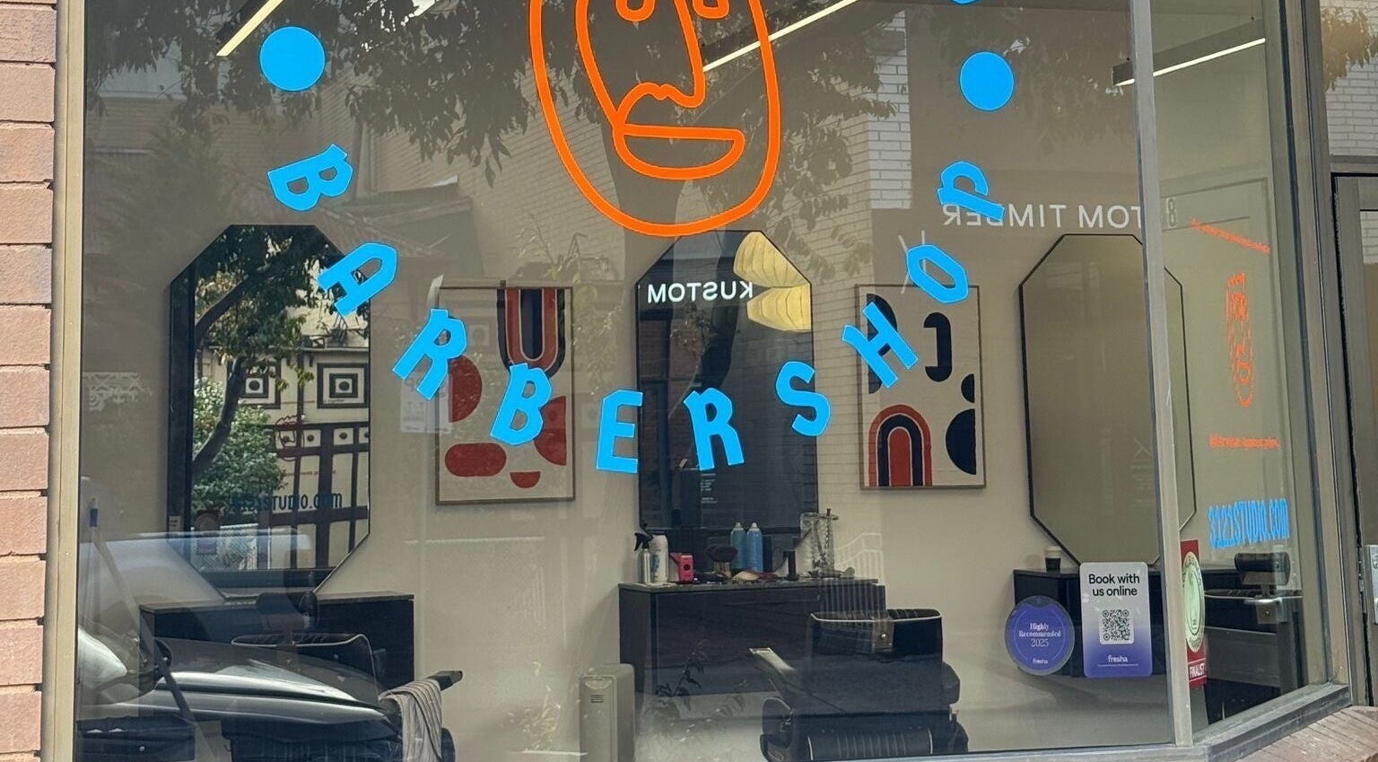 Exterior of 3121 Studio, a trendy barbershop in Melbourne, Victoria, AU with colorful window signage.