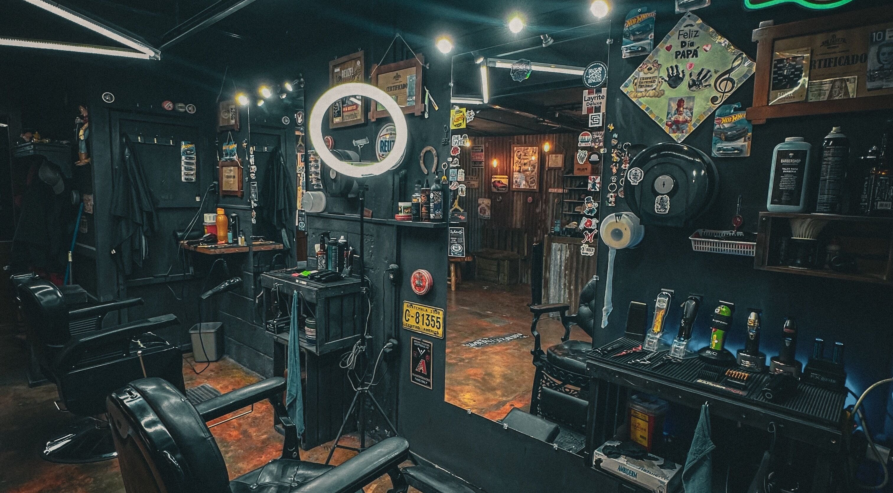 Interior de The Barber en Tecpán, Chimaltenango, GT, mostrando sillas y un espejo iluminado.