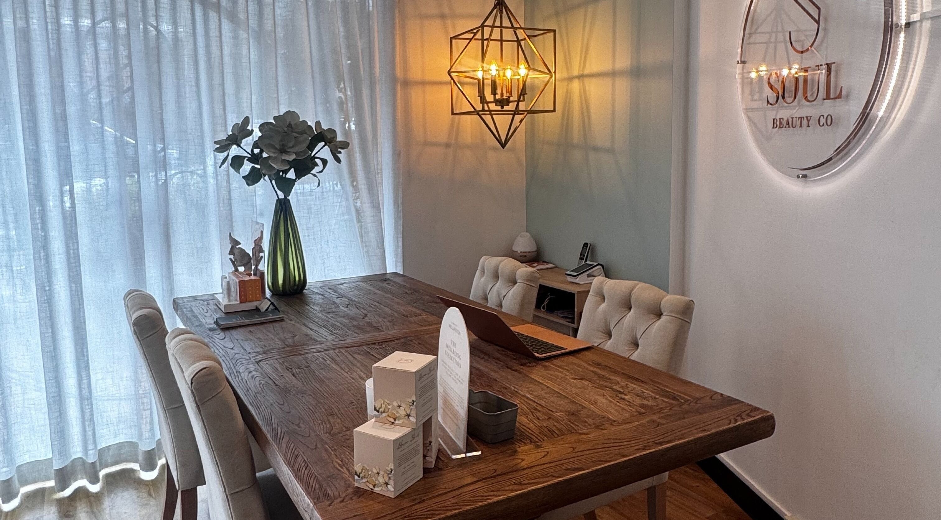 Elegant sitting area at Soul Beauty Co, Edge Hill, Queensland, AU featuring a wooden table and decorative lighting.