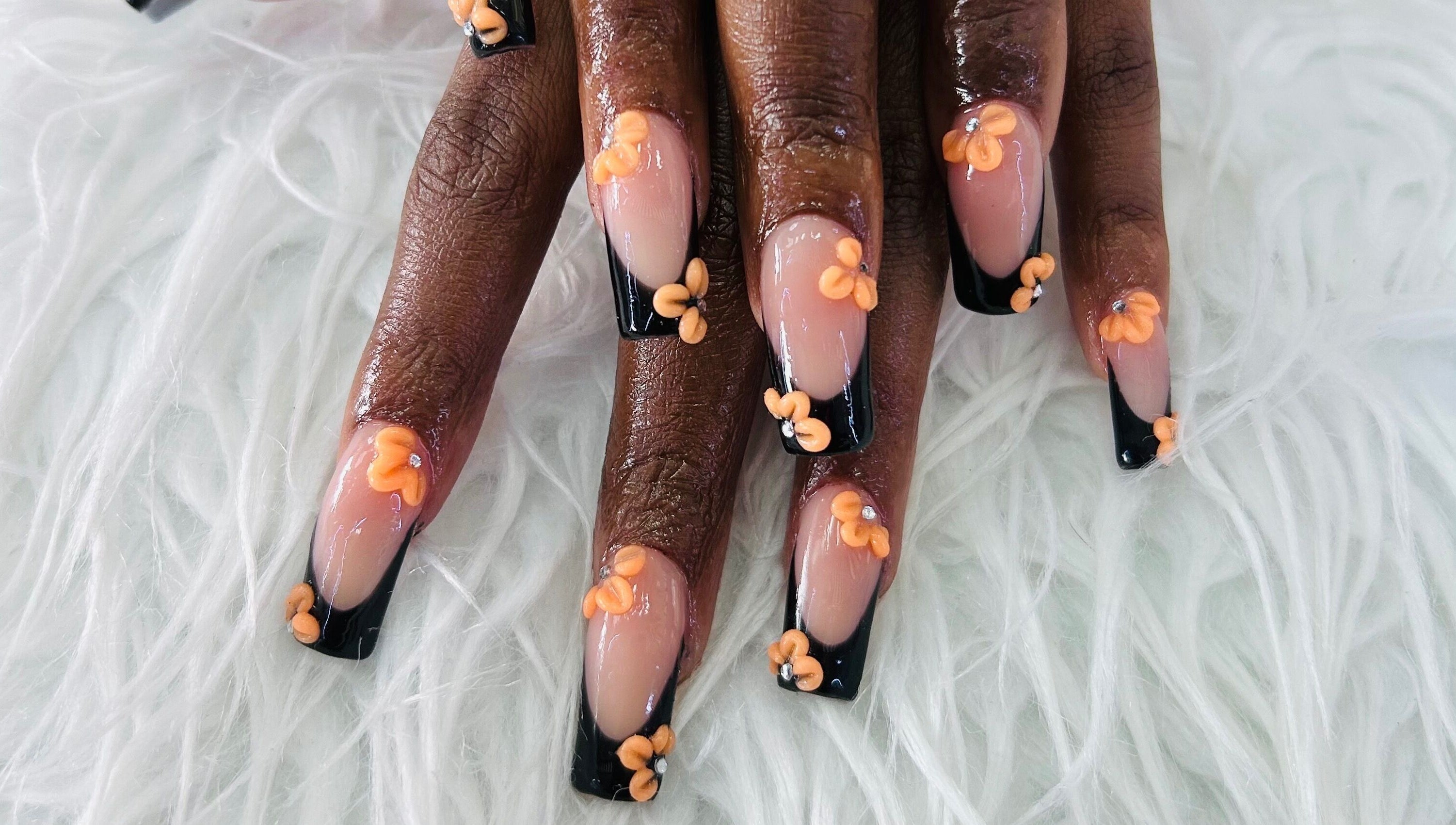 Stylish floral nail art at Essentials by L.T, Midrand, Gauteng, ZA featuring orange flowers on black tips.
