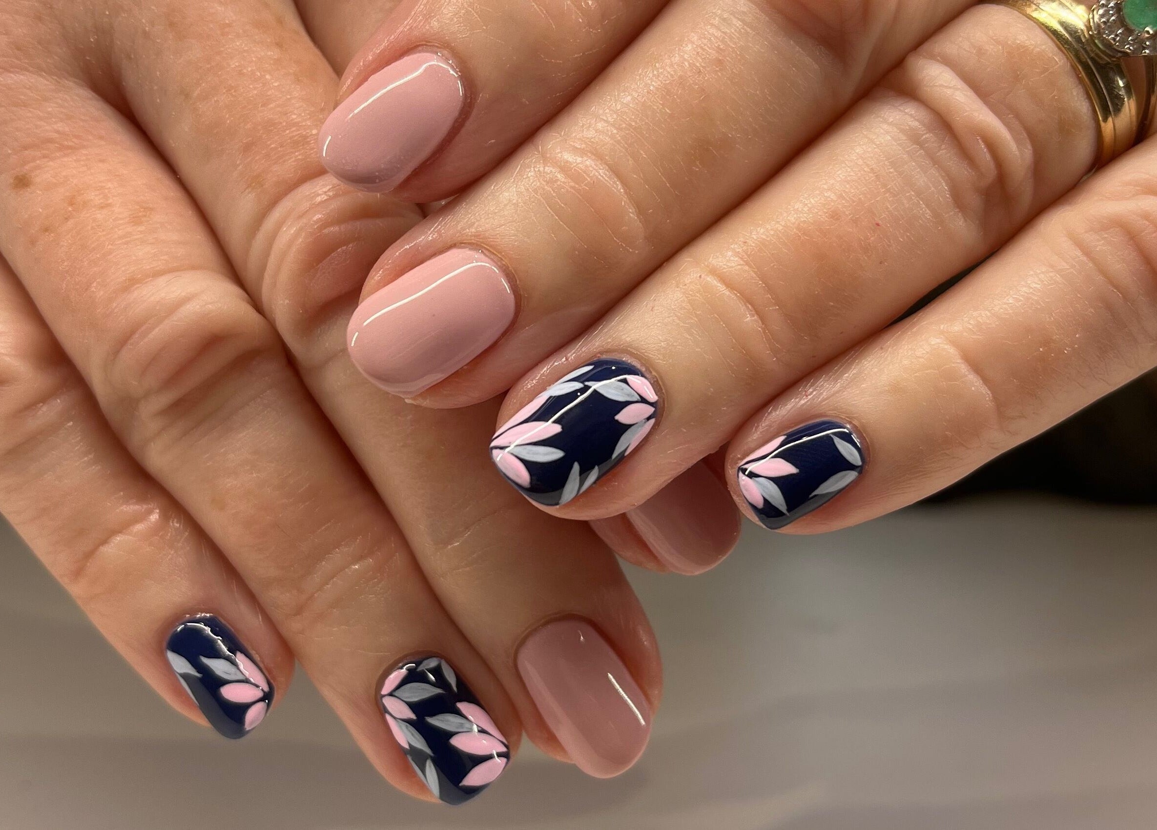 Elegant floral nail art at The Beauty Shed in West, England, GB. Perfectly manicured hands with pink and navy tones.