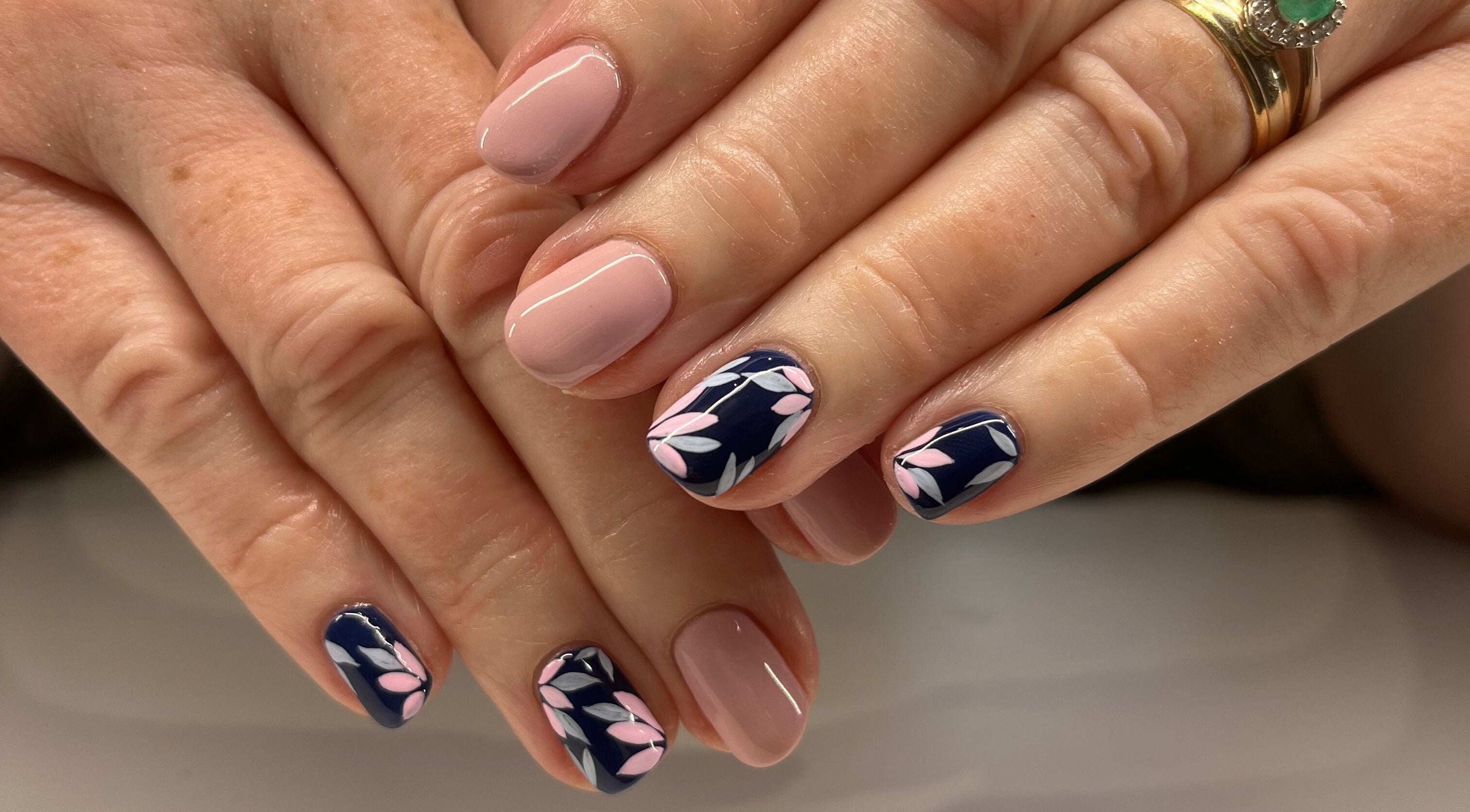 Elegant floral nail art at The Beauty Shed in West, England, GB. Perfectly manicured hands with pink and navy tones.