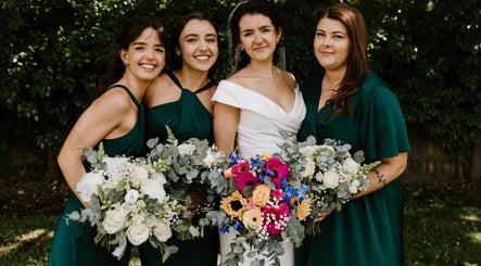 Bridesmaids in emerald dresses with floral bouquets at JOAM Glow London Mobile Spray Tanning Sienna X, London, England, GB.