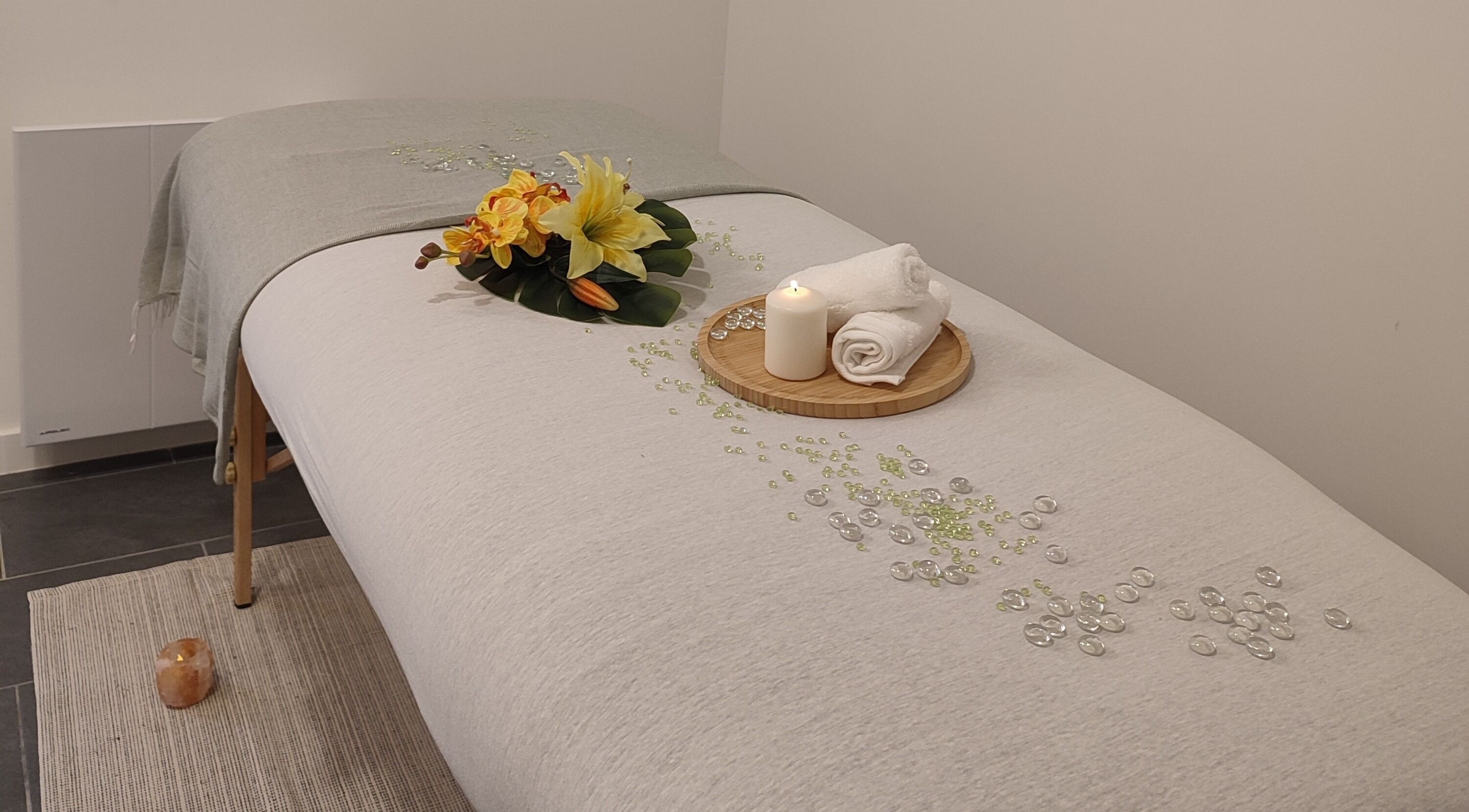 Table de massage apaisante à Énergie d'être, Auxy, Centre-val De Loire, FR, avec fleurs et bougie.