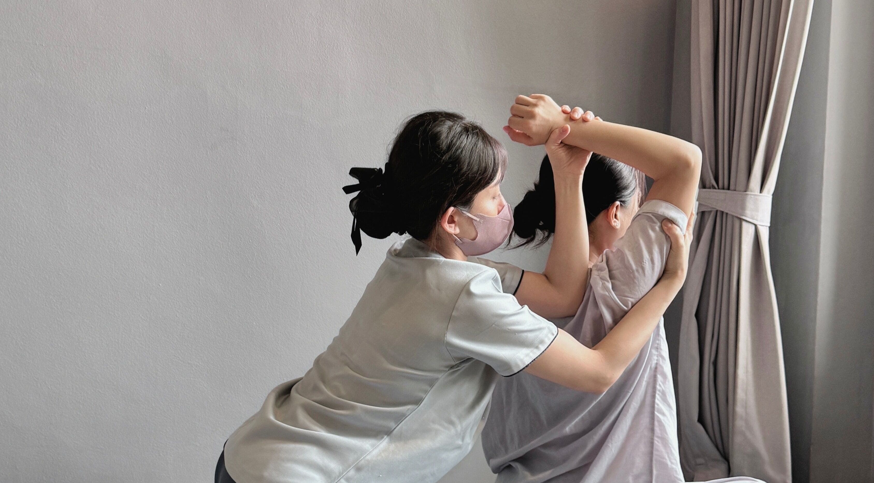 Therapist at Sabaai Sabaai Traditional Thai Massage in Raffles Place, SG, stretching client's arm.