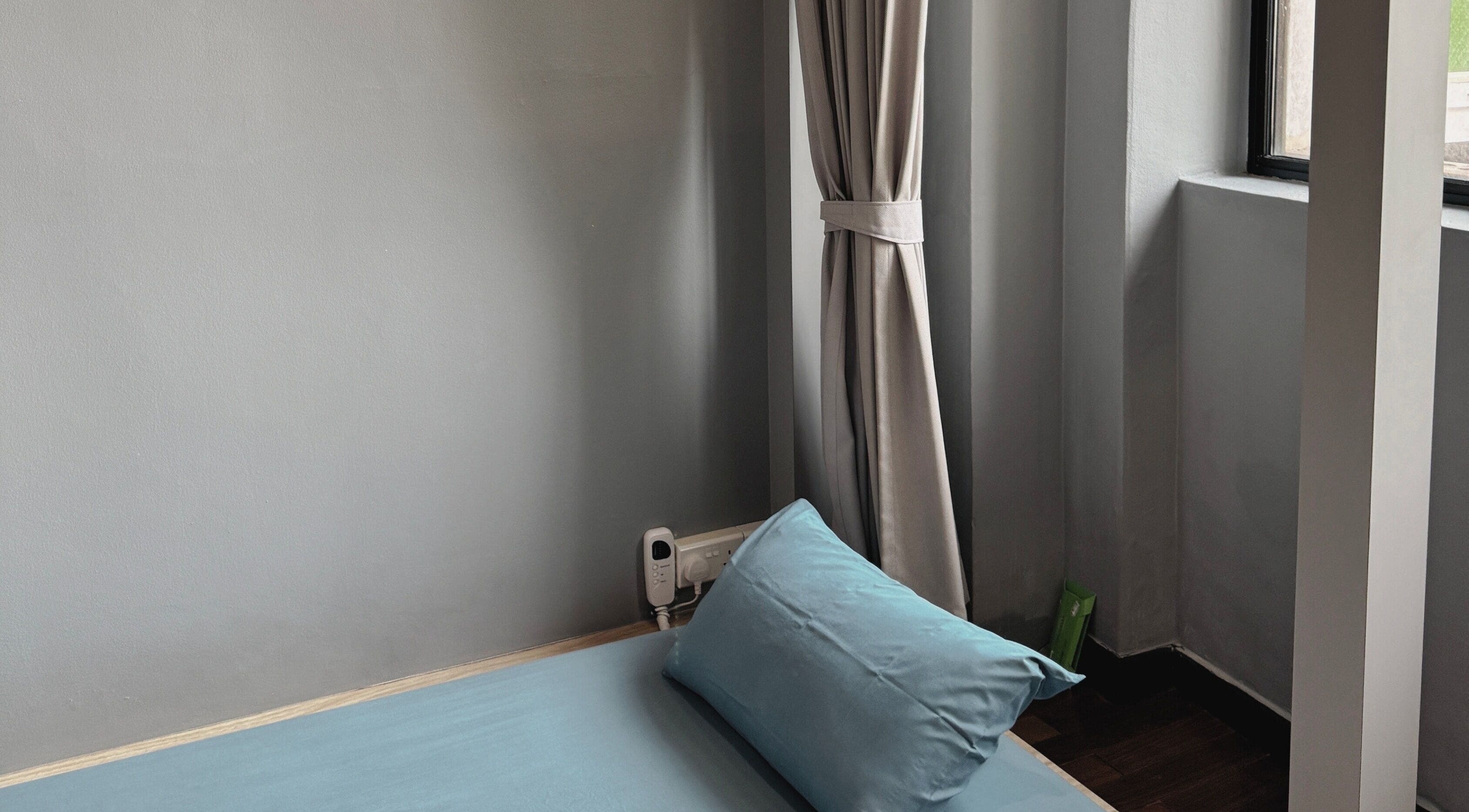 Cozy massage room at Sabaai Sabaai Traditional Thai Massage, Raffles Place, SG with blue pillow and grey curtains.