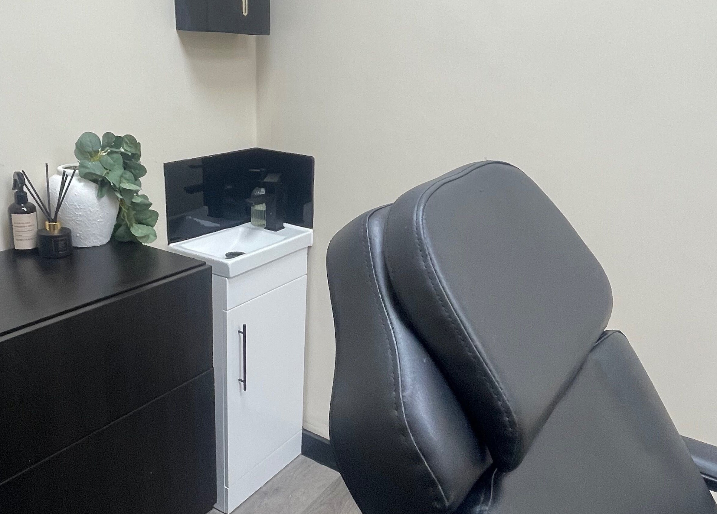 Stylish treatment room at DMW Aesthetics in Stanford-le-hope, England, GB, featuring a modern black chair.