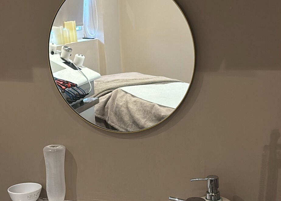 Mirror reflecting a cozy treatment room at The Beauty Hutmcr in Dukinfield, England, GB.