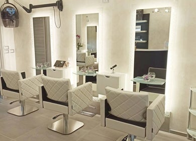 Interno elegante di Kromatik Hair Studio a Ferrara, Emilia-romagna, IT. Sedie bianche e specchi illuminati.