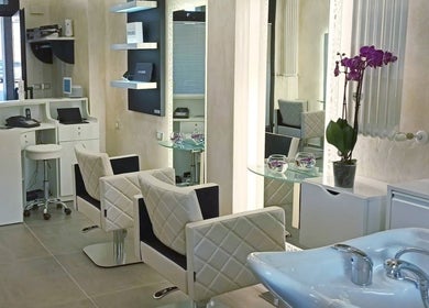 Interno elegante di Kromatik Hair Studio a Ferrara, Emilia-romagna, IT, con sedie imbottite e decorazioni moderne.
