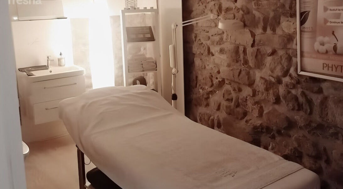 Salle de soin apaisante à Lumin'Essences, Lutry, Vaud, CH avec murs en pierre et table de massage.