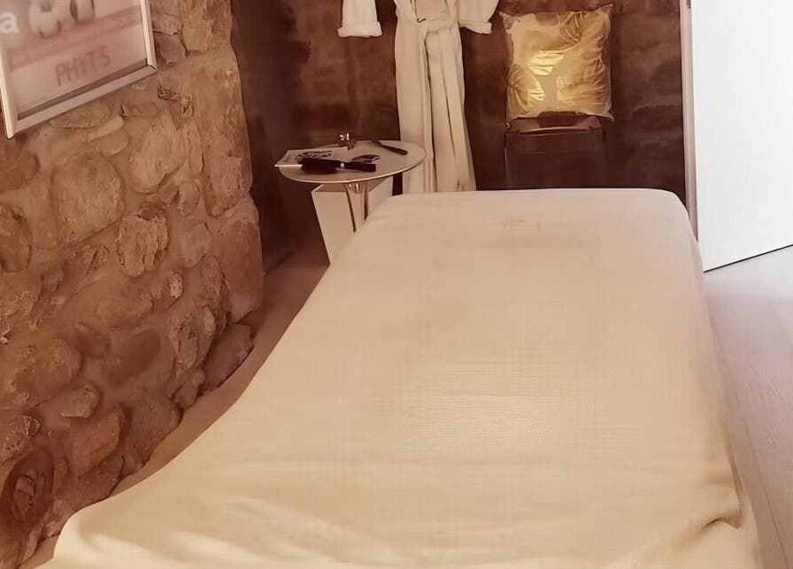 Salle de soins en pierres naturelles à Lumin'Essences, Lutry, Vaud, CH, avec table de massage blanche.