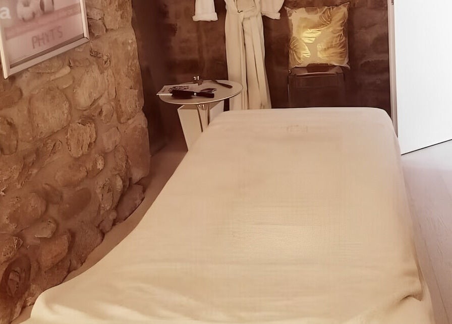 Salle de soins en pierres naturelles à Lumin'Essences, Lutry, Vaud, CH, avec table de massage blanche.