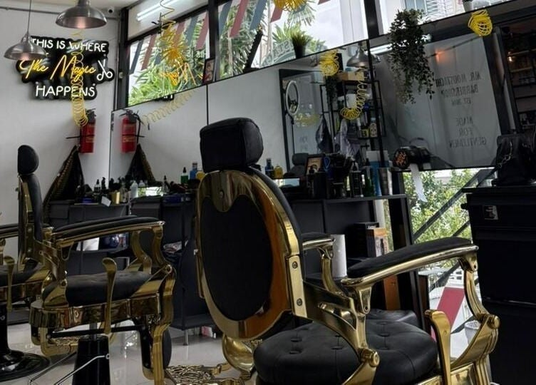 Interior elegante de Mr. Moustache Barbershop en Santiago De Los Caballeros, con sillas de barbero doradas.