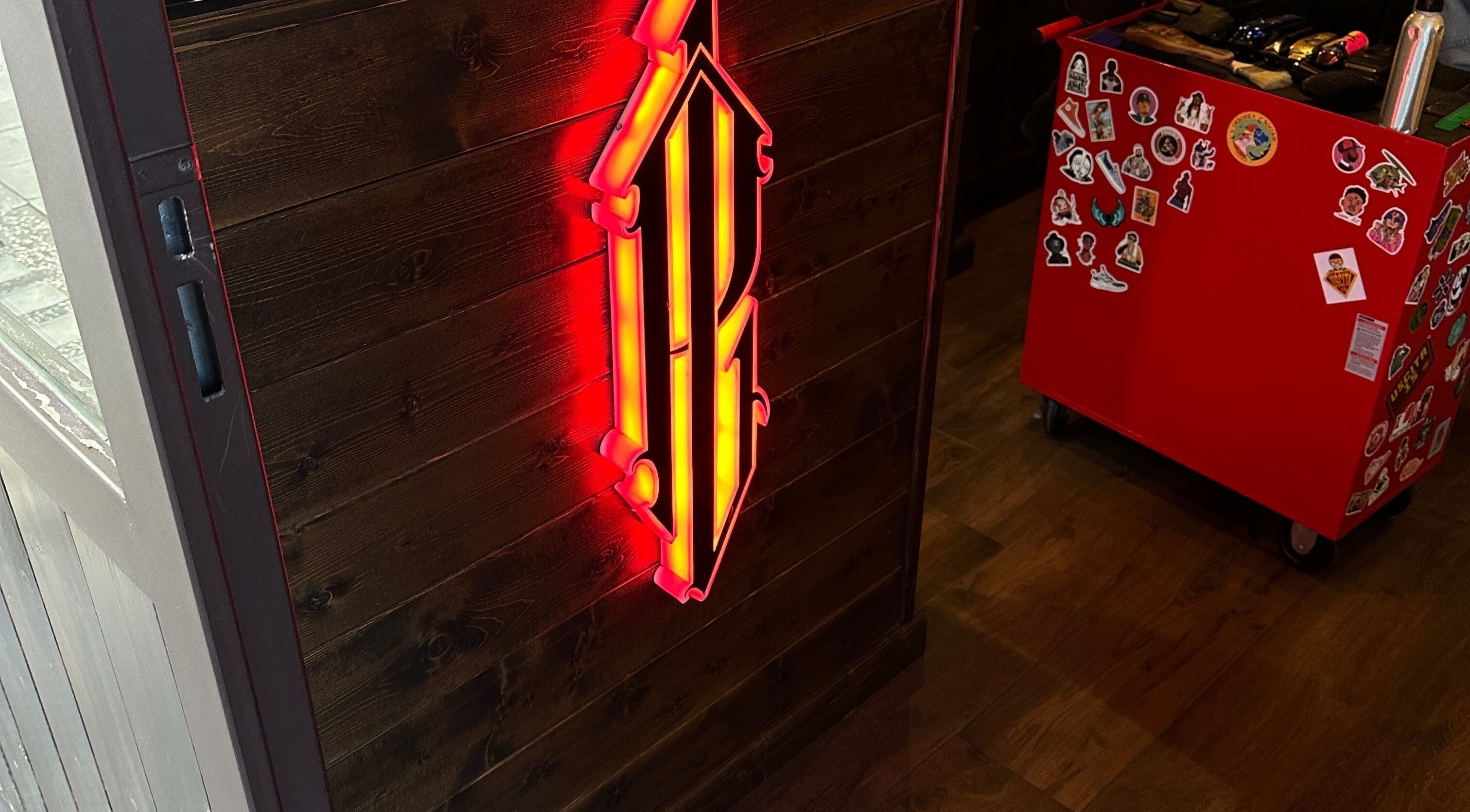 Insegna luminosa all'interno di Peloloco Tiburtina, Roma, Lazio, IT, accanto a un cartello rosso decorato.