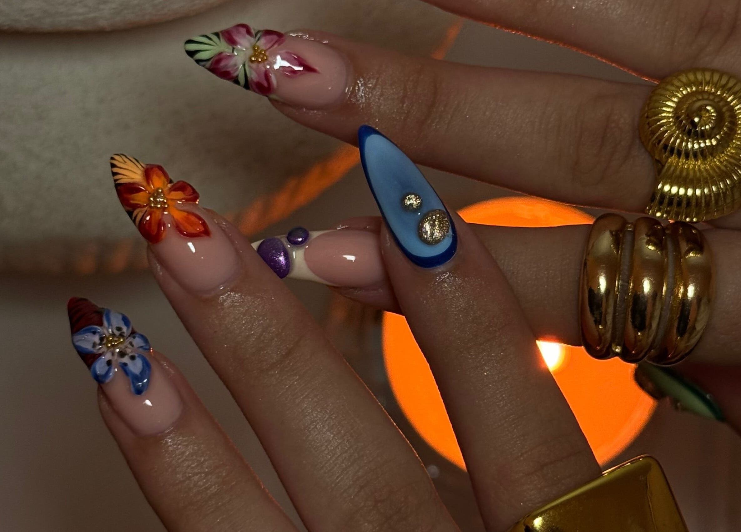 Intricate floral nail art at Gemi Nailz, Cleveland, Queensland, AU, showcasing vibrant designs and gold accessories.