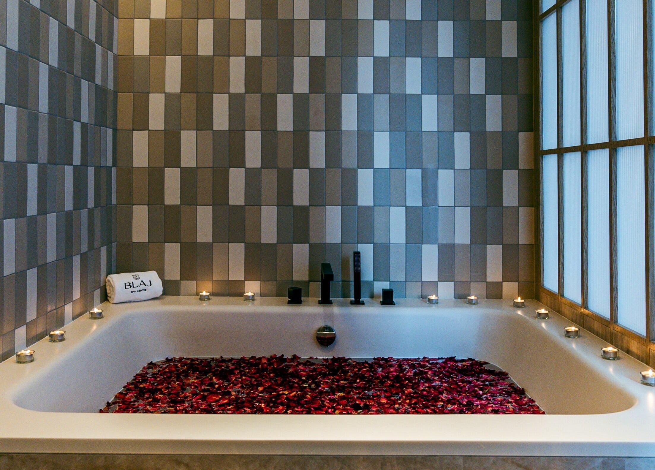 Luxurious rose petal bath at Blaj Spa, Dubai, AE with ambient candles for a serene spa experience.