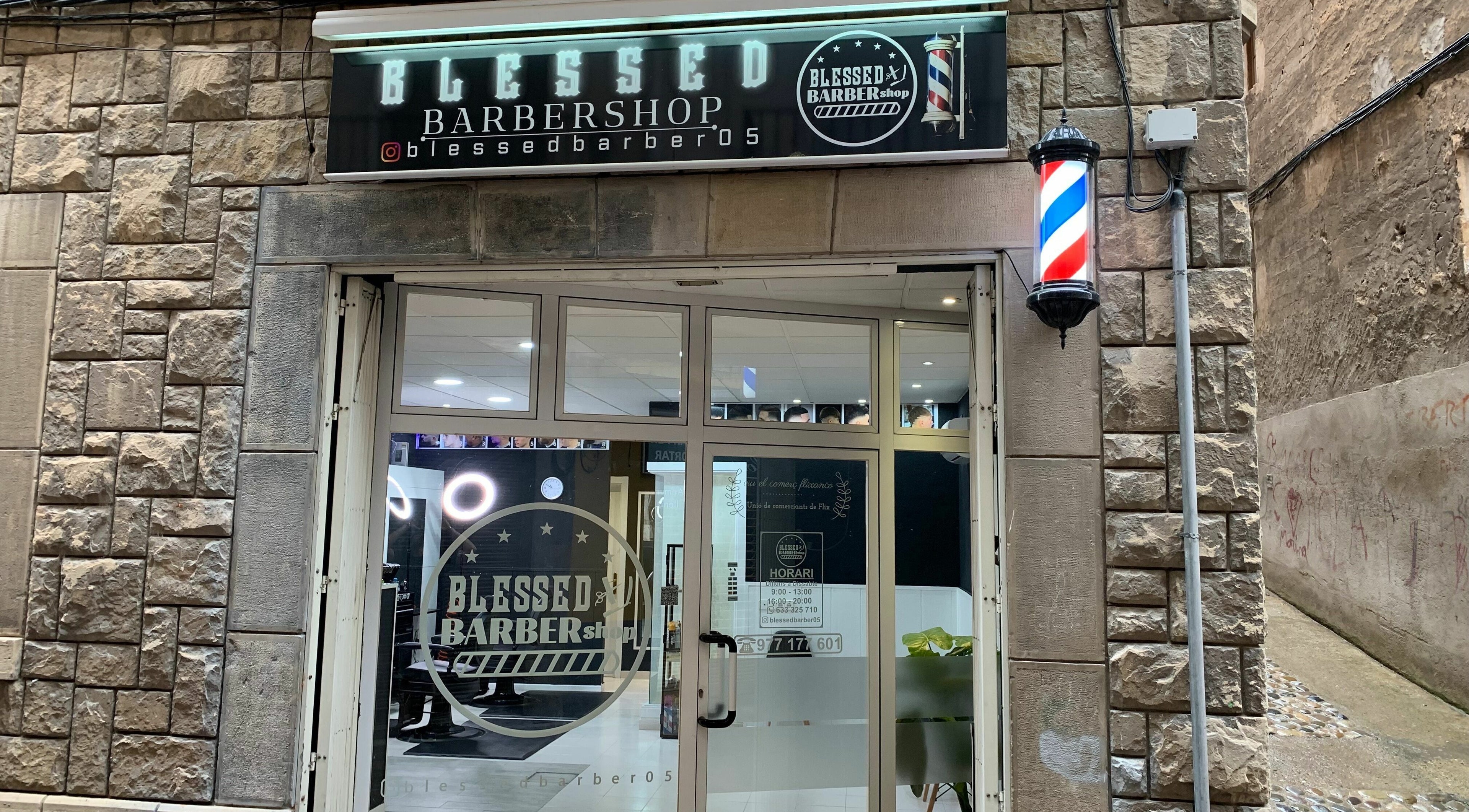 Entrada iluminada de Blessed BarberShop en Flix, Catalunya, ES con letrero y poste clásico.