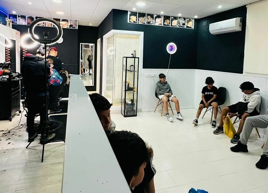 Interior moderno de Blessed BarberShop en Flix, Catalunya, ES, con clientes esperando cortes de cabello.