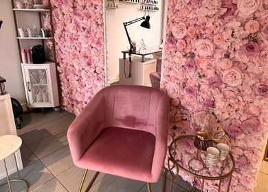 Intérieur élégant avec fauteuil rose et murs fleuris chez G Beauty Geneve, Vernier, Genève, CH.