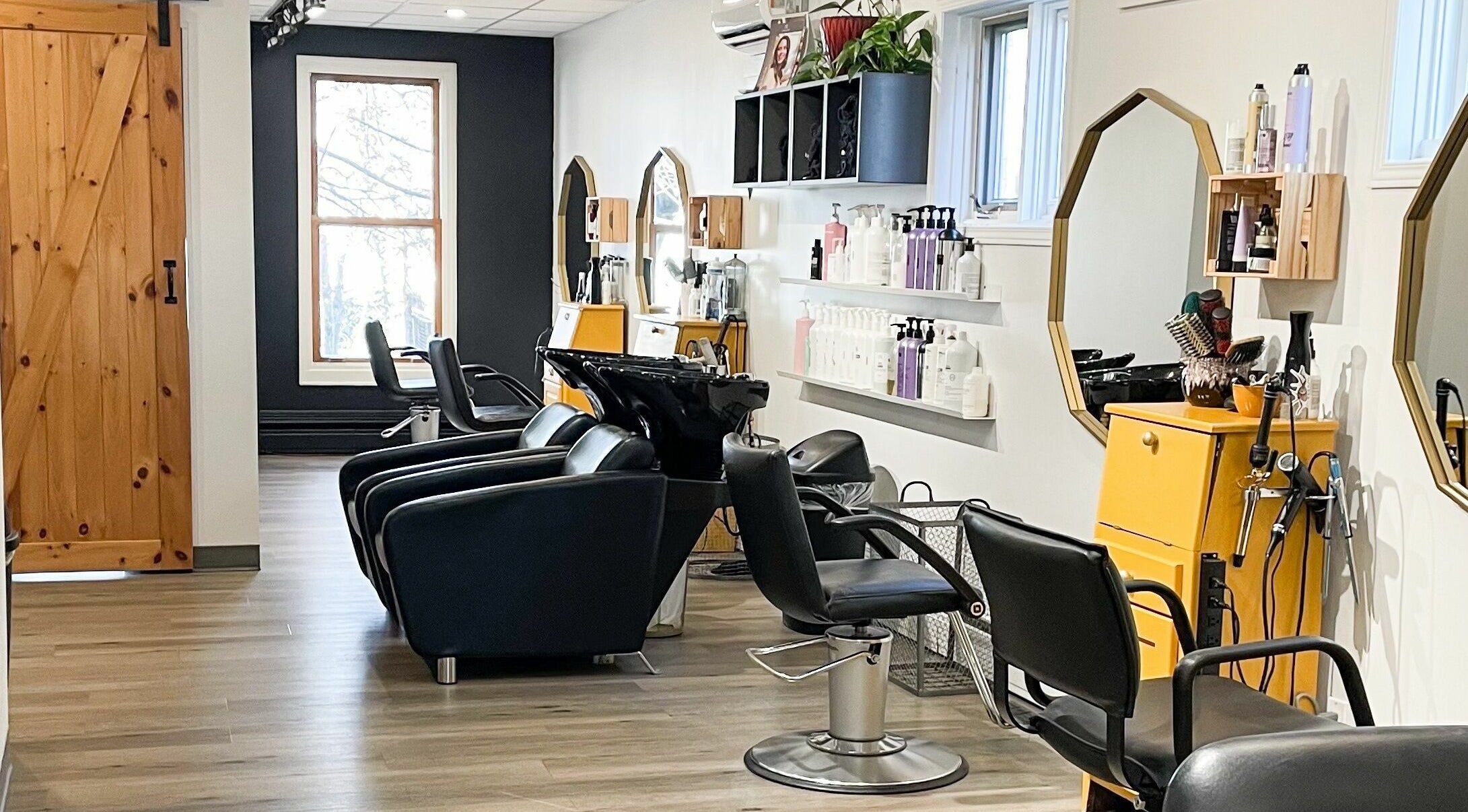 Intérieur moderne de La P'tite Coiffe à Rimouski, Québec, CA, avec des fauteuils de salon élégants.
