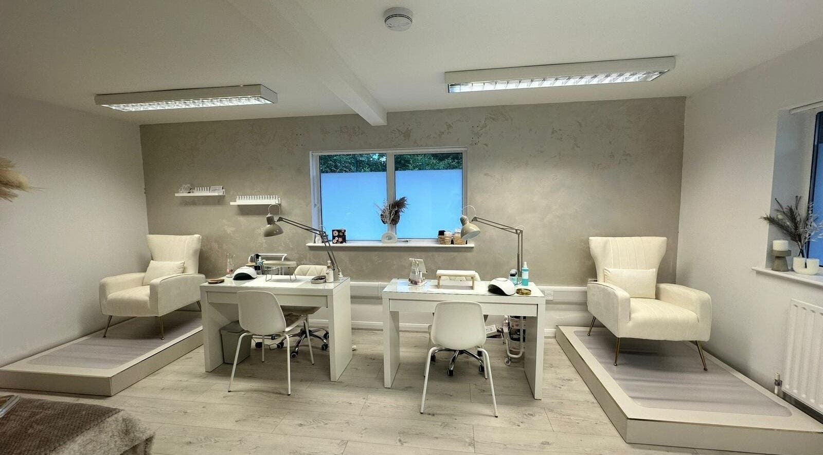 Modern interior of JM Aesthetically Yours in Hilton, England, GB with stylish chairs and manicure stations.