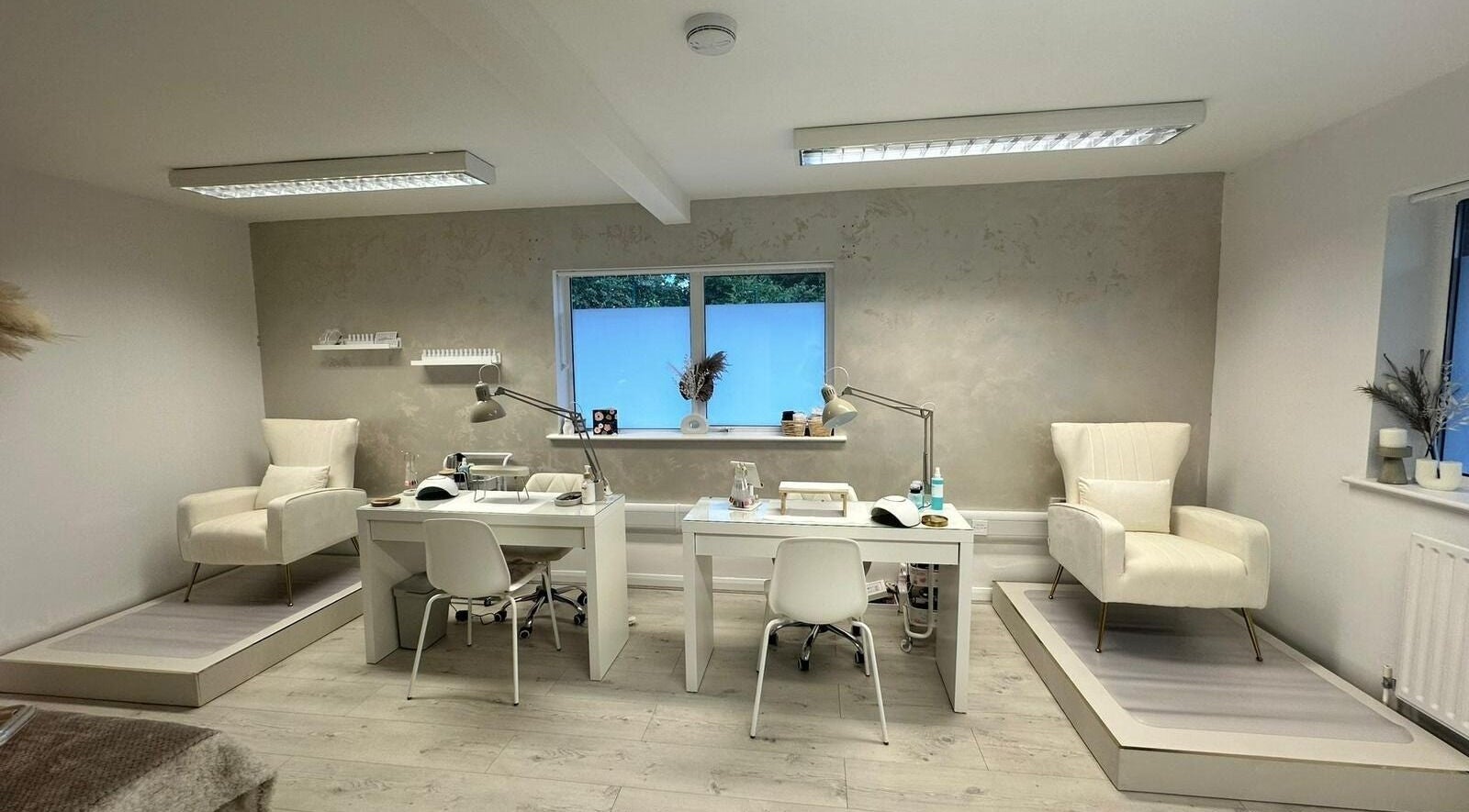 Modern interior of JM Aesthetically Yours in Hilton, England, GB with stylish chairs and manicure stations.