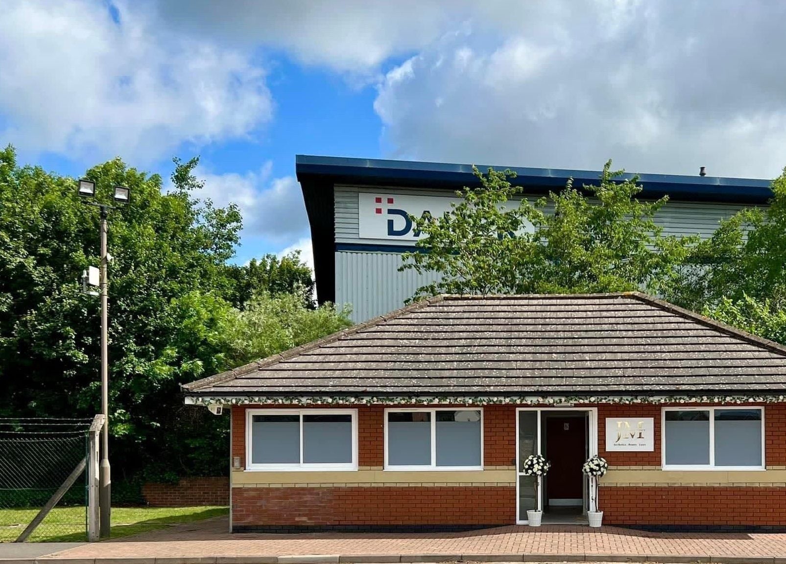 Front view of JM Aesthetically Yours in Hilton, England, GB featuring a quaint brick building with lush greenery.