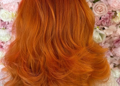 Vibrant orange hair styled at Divine Hair and Aesthetics, Middlesbrough, England, GB, against a floral backdrop.