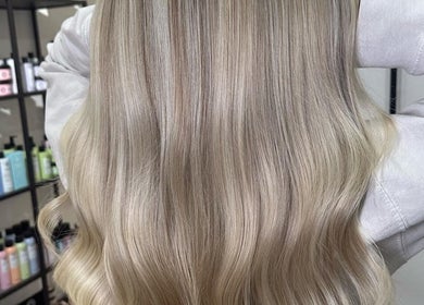 Long blonde hair styled elegantly at Luke East Hair in Birmingham, England, GB. Professional haircare products visible.